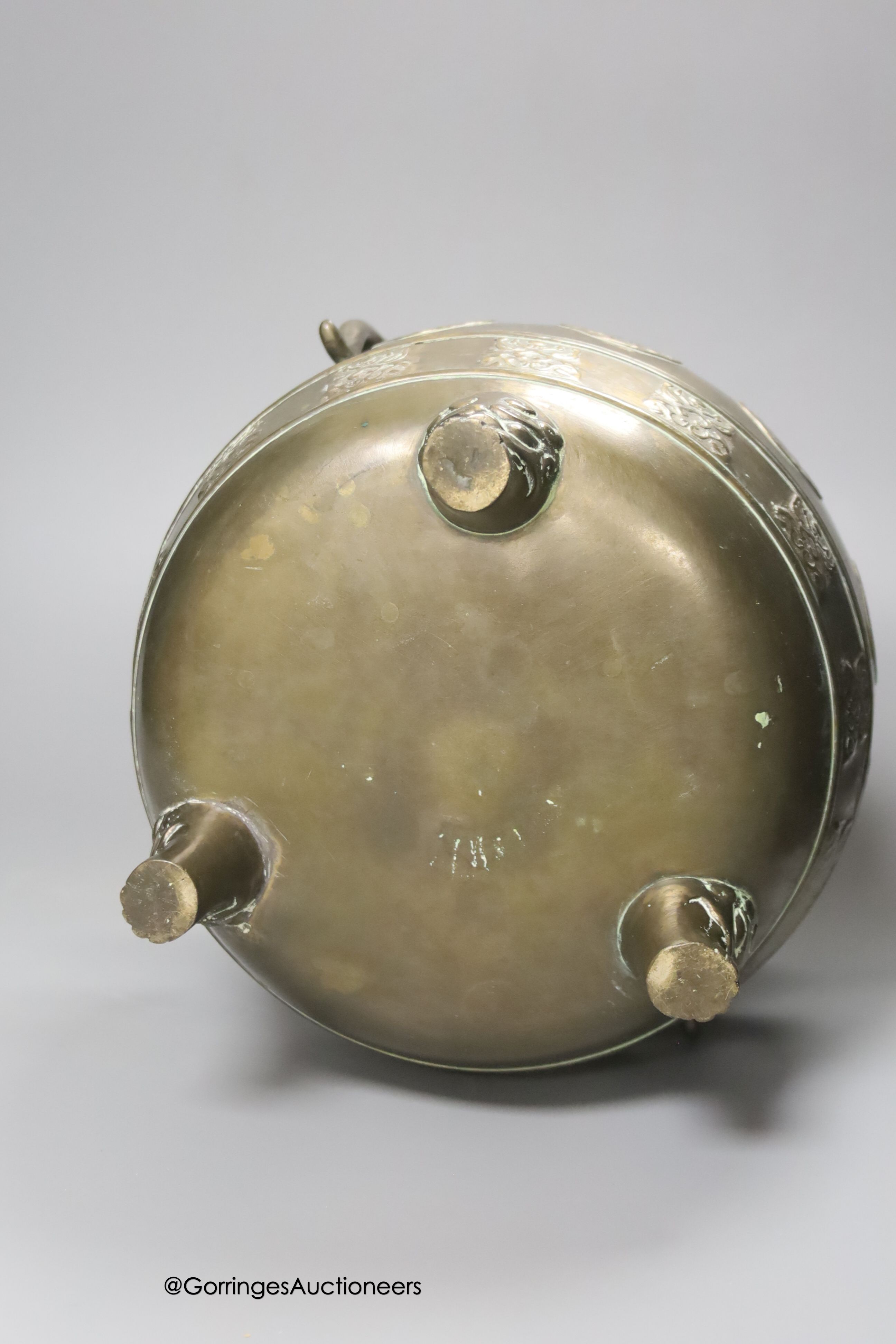 A Chinese or Japanese bronze two handled vessel, on cast feet, 22cm